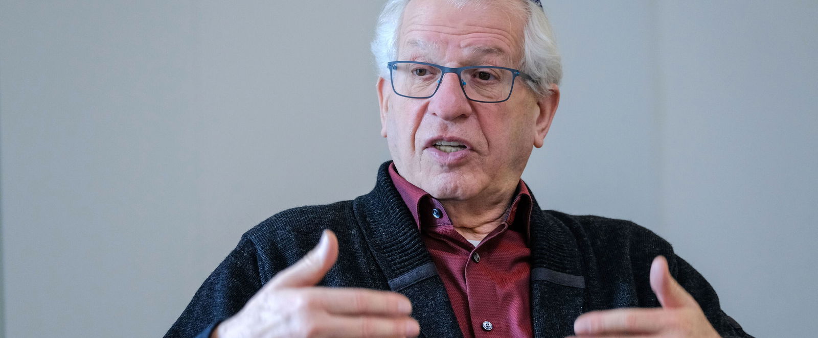 Ein älterer Mann mit Kippa spricht und gestikuliert dabei.