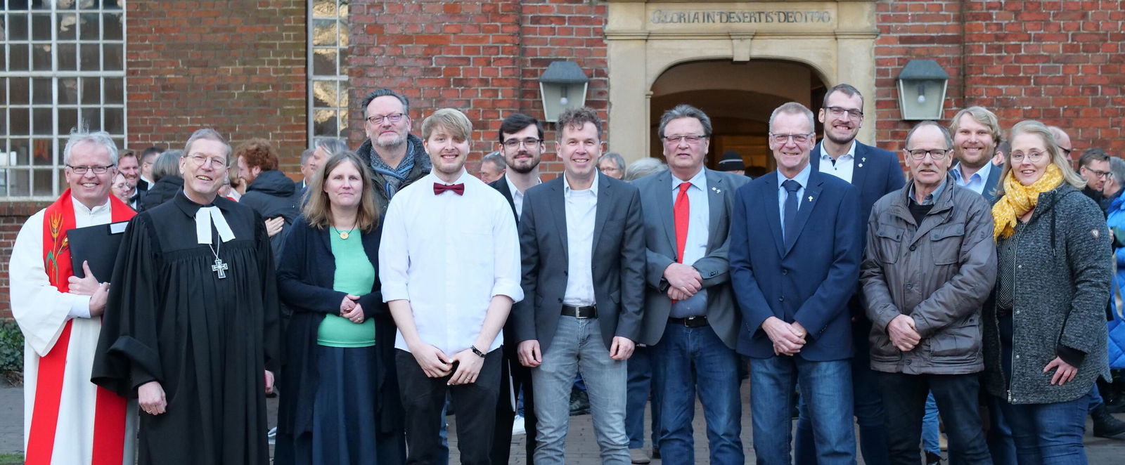 Eine große Gruppe posiert vor einer Kirchentür.