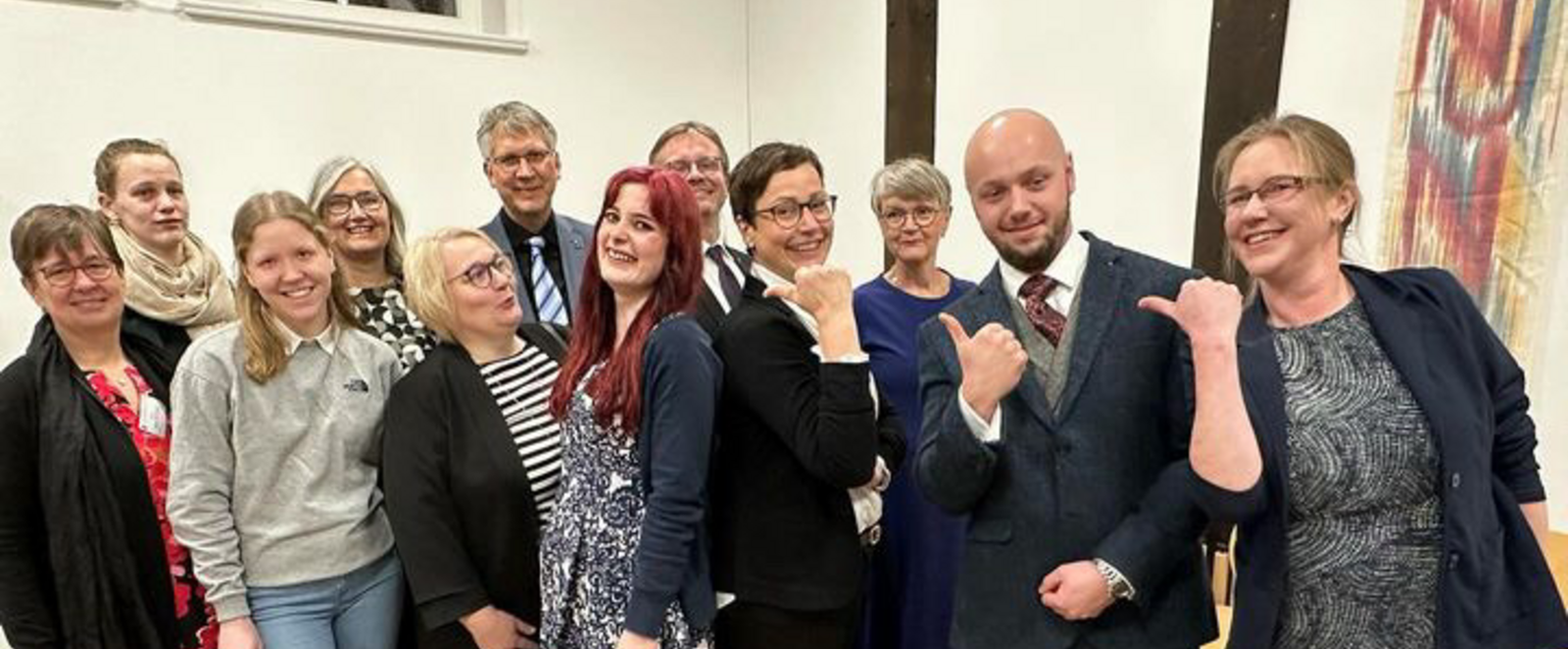 Ein Gruppenfoto mit Menschen in einem Raum mit hellen Wänden. 