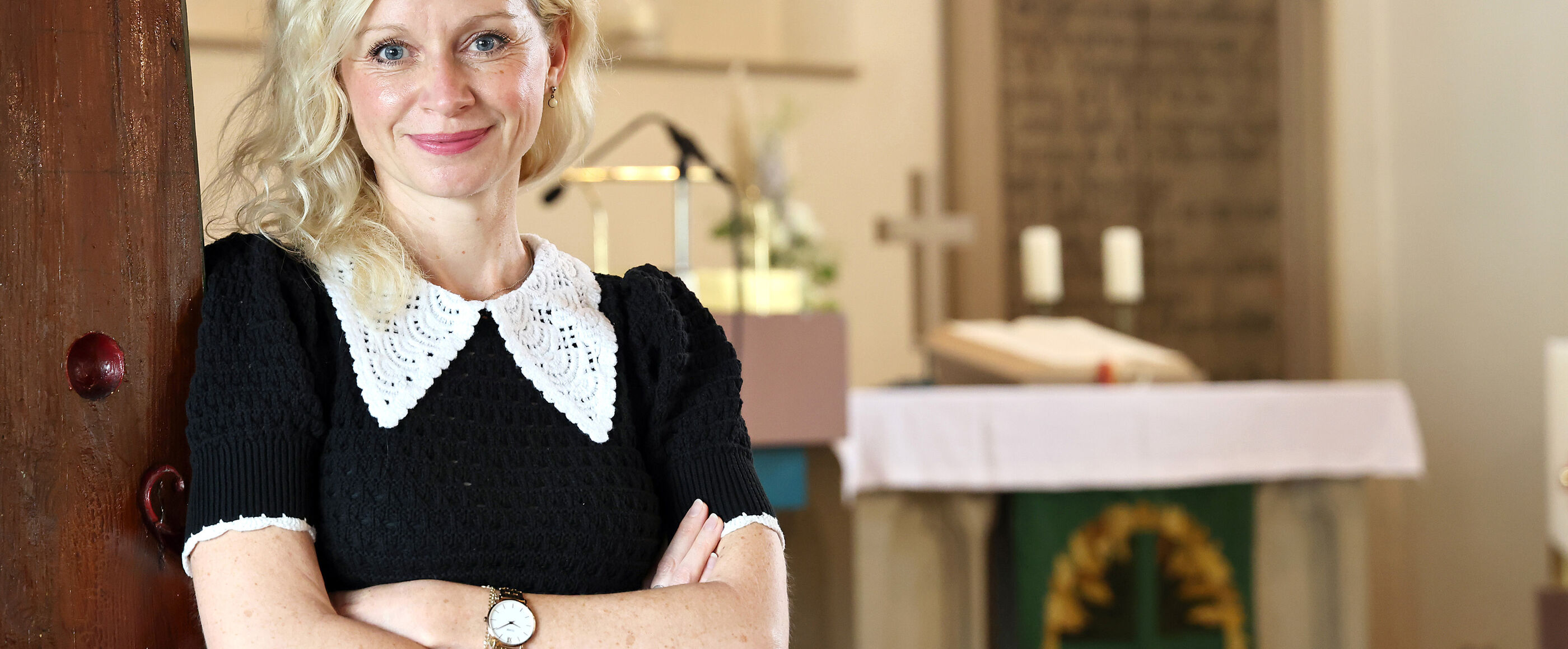 Eine als Frau lesbare Person lehnt an einer Säule in einer Kirche.