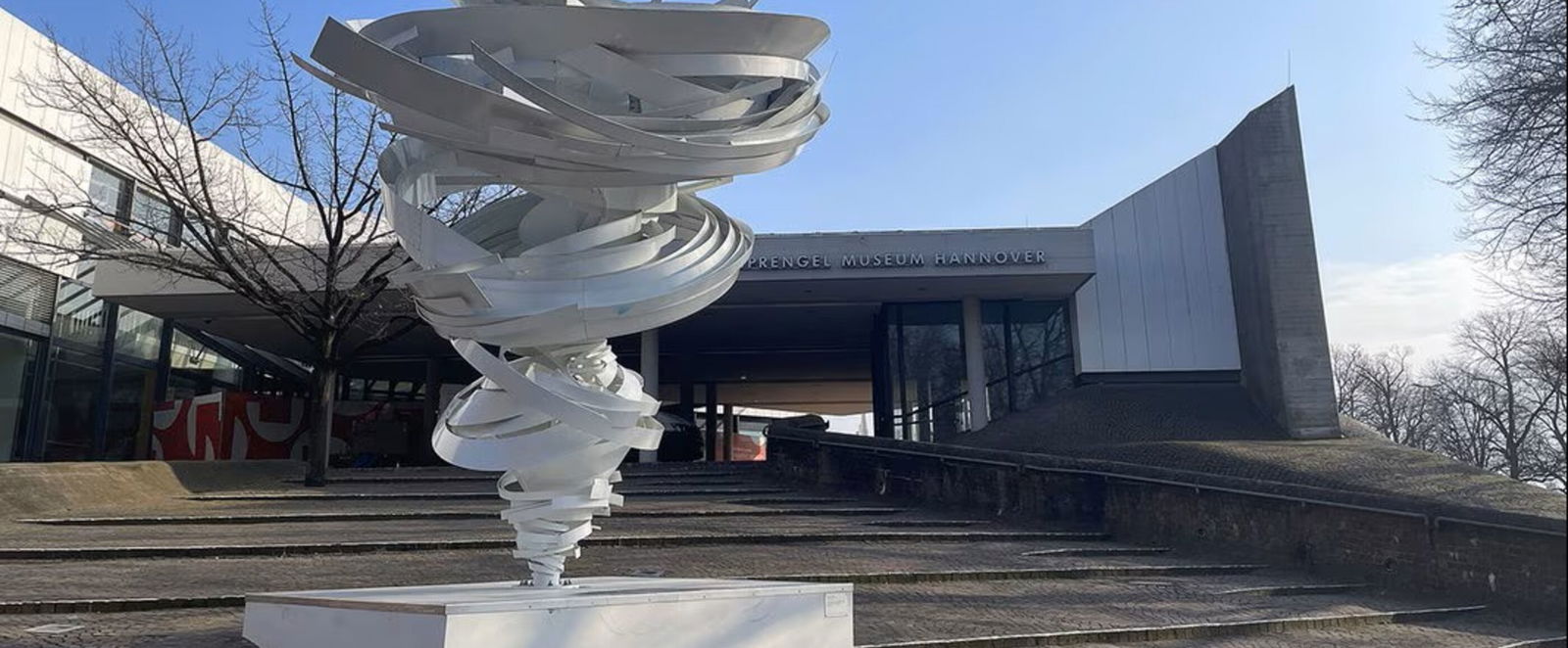 Eine wirbelsturmartige Skulptur vor dem Eingang eines Museums (Sprengel Museum).