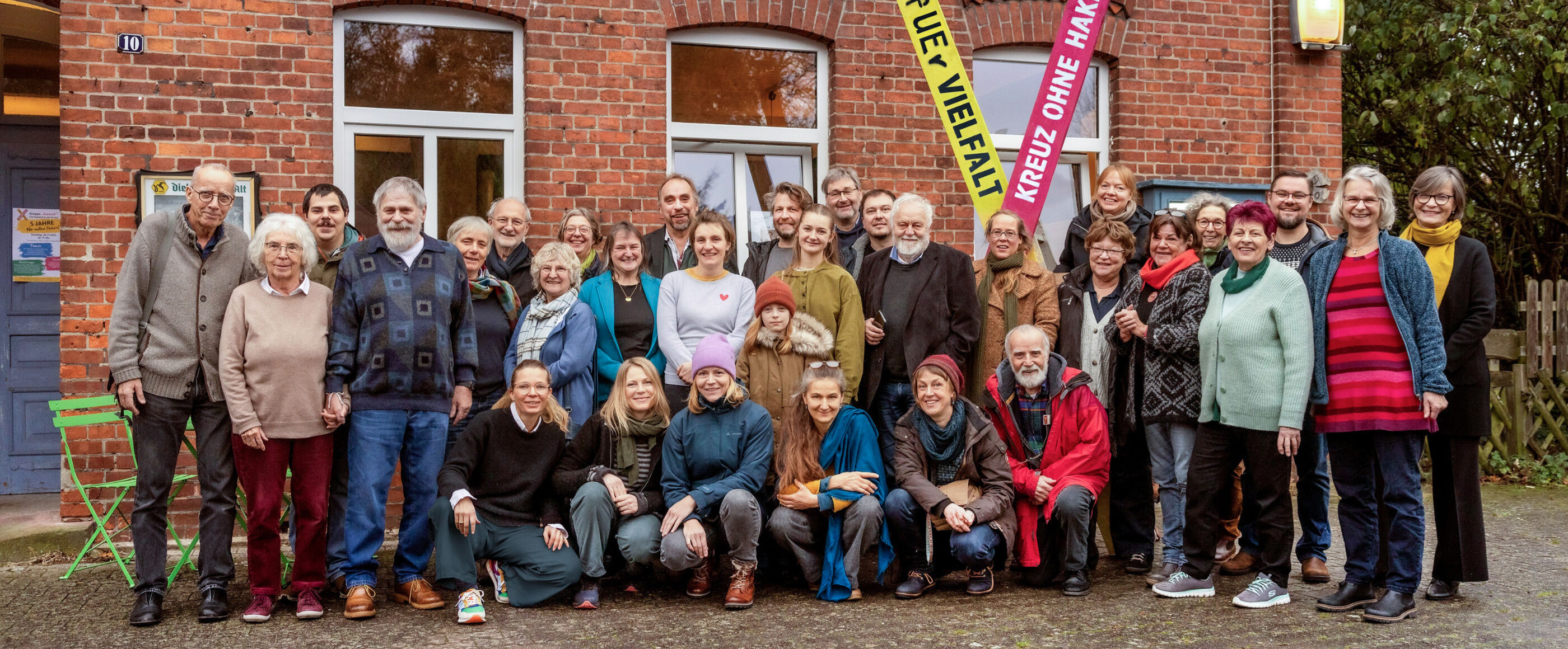 Eine Gruppe von Menschen steht vor einem Backsteinhaus.