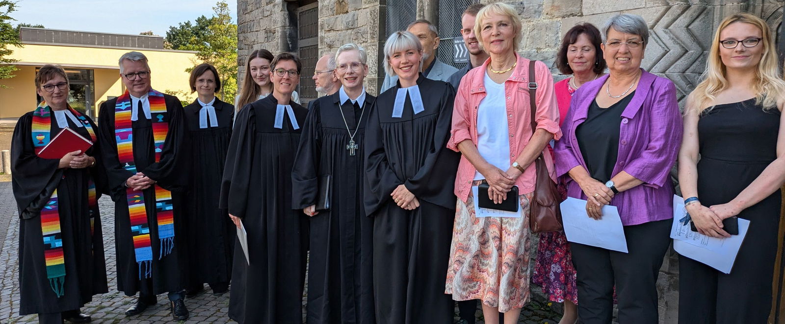 Eine Gruppe von Menschen vor einer Kirche in Talaren.