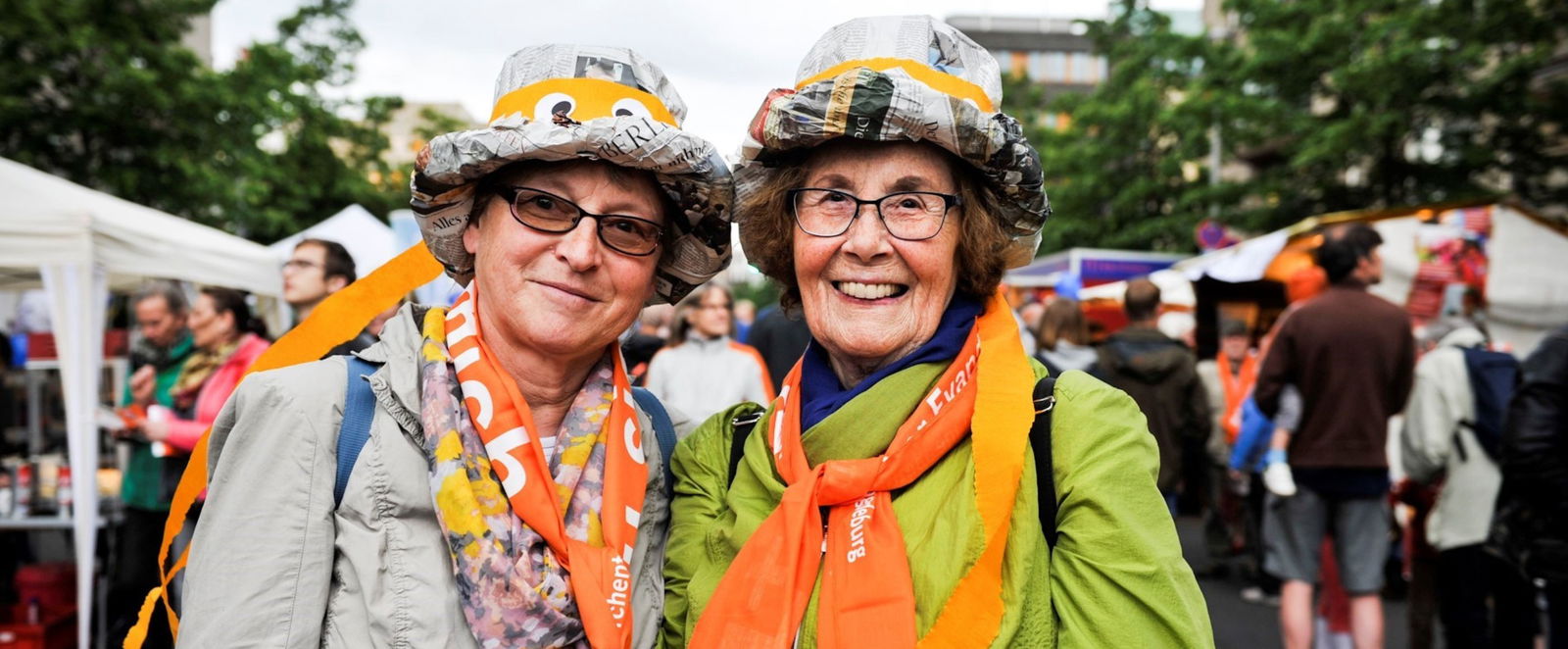 Zwei lächelnde Frauen stehen zwischen Ständen