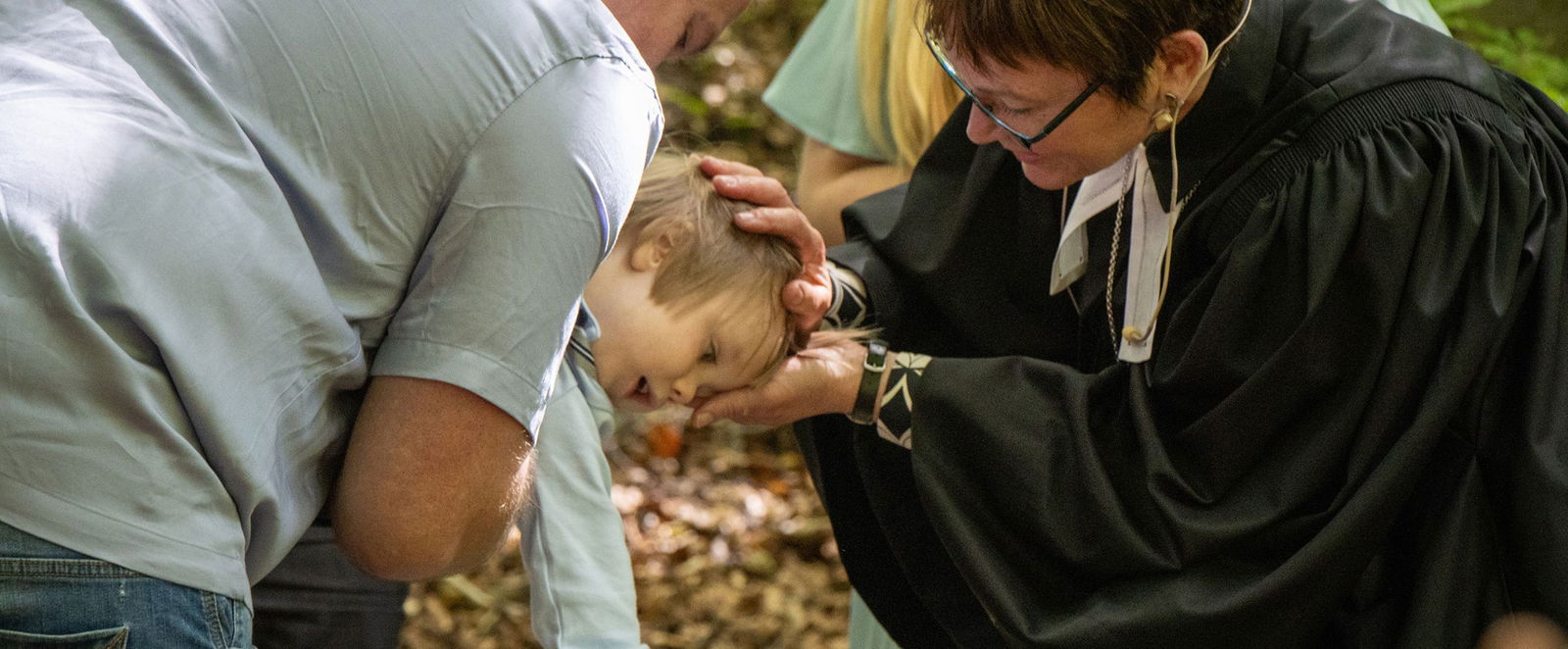 Ein Kind wird von einer Pastorin getauft.