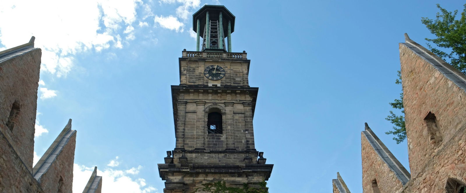 Ein Kirchturm mit einer Uhr vor blauem Himmel.