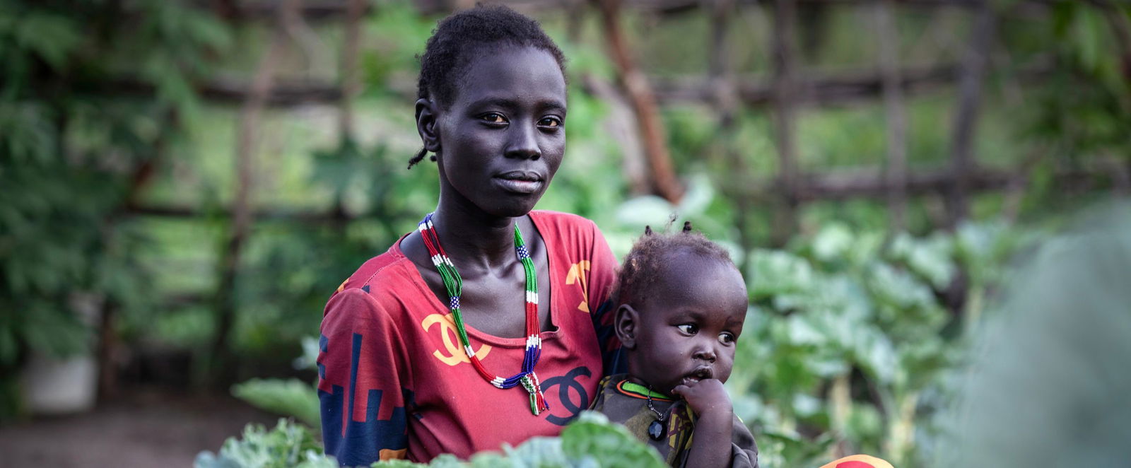Eine farbige Frau hält ein Kind im Arm.