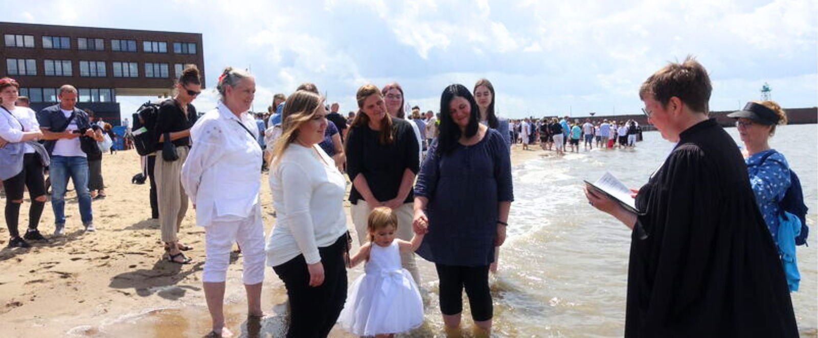 Menschen mit einer Pastorin an einem Flussstrand.
