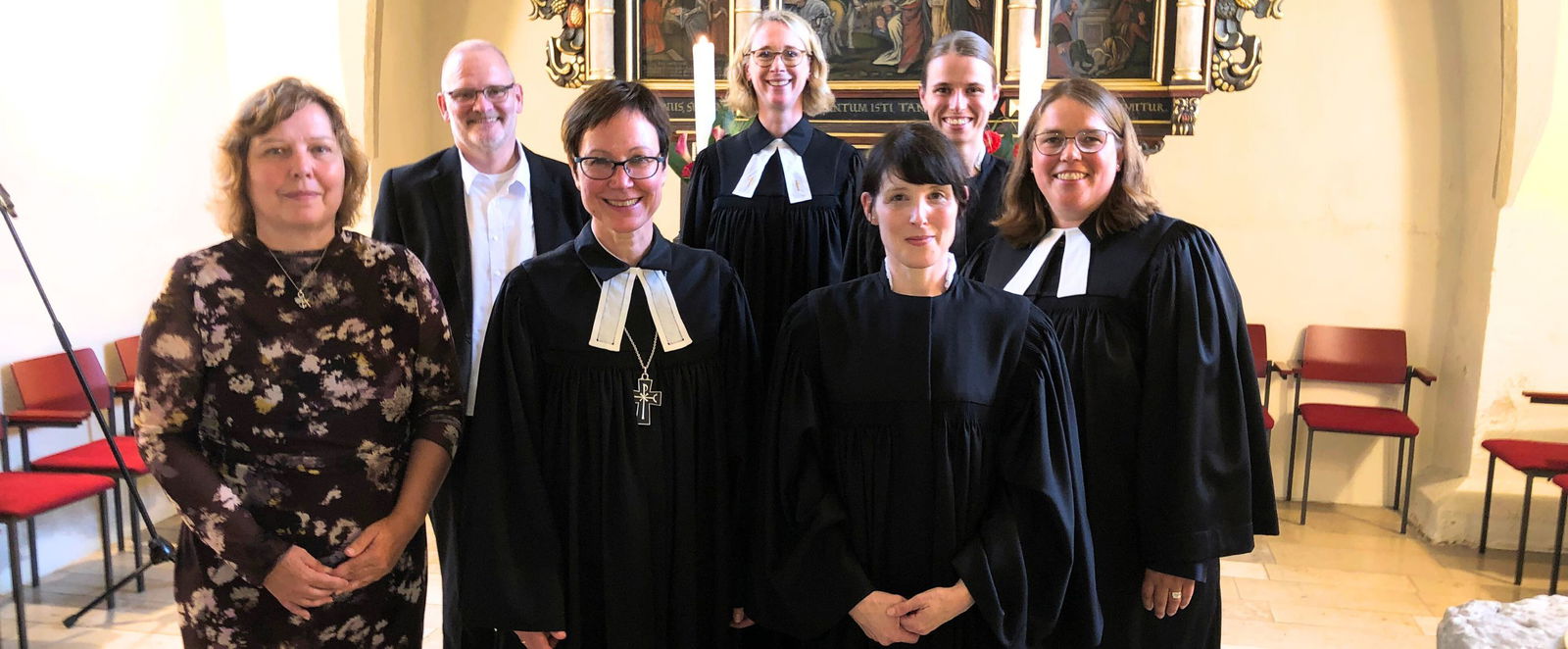 Eine Gruppe von Menschen in Talaren steht in einer Kirche.