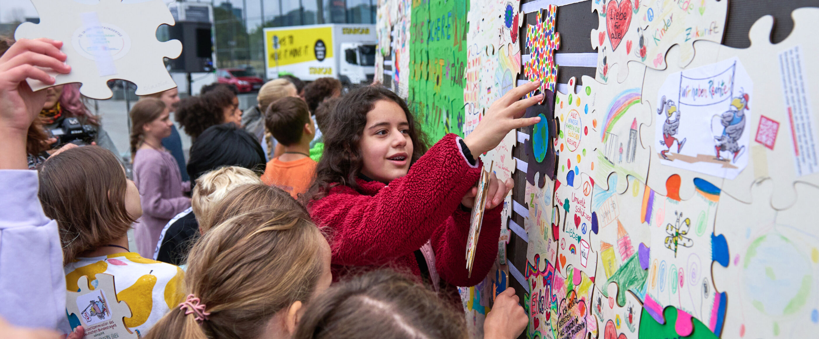 Kinder kleben Puzzleteile an eine Wand.