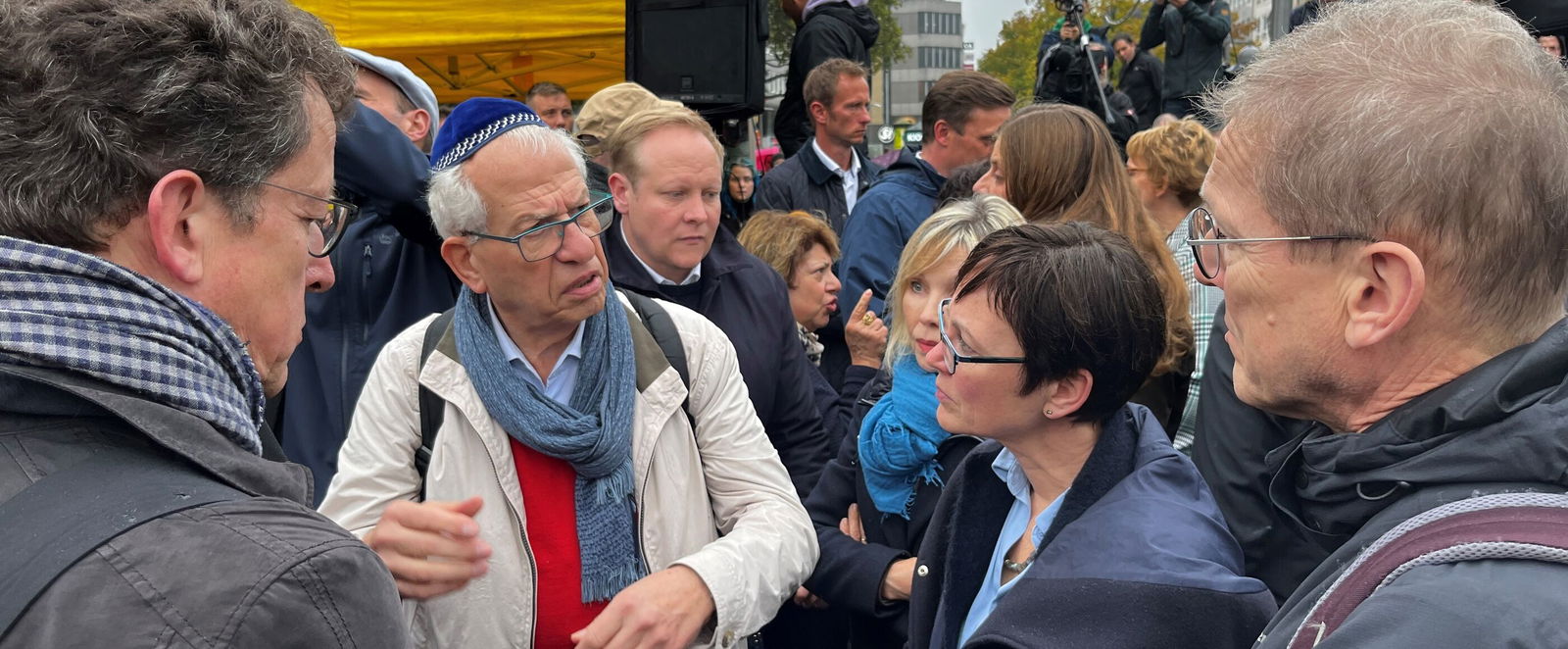 Mehrere Menschen stehen diskutierend bei einer Demo zusammen.