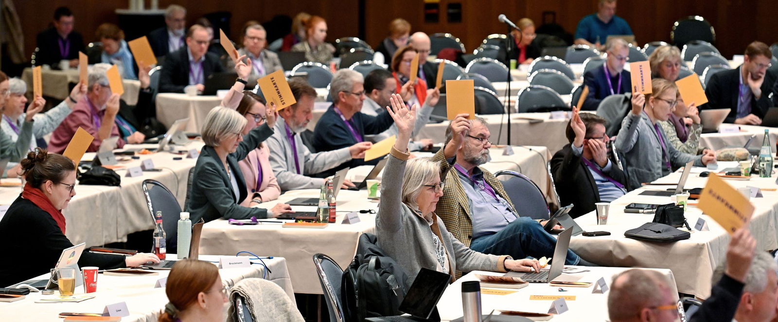 Menschen stimmen ueber etwas ab und halten Karten in die Hoehe