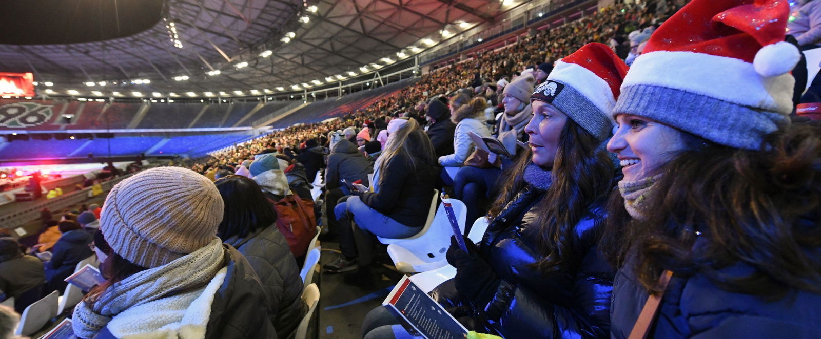 Menschen mit Weihnachtsmuetzen in einem Stadion