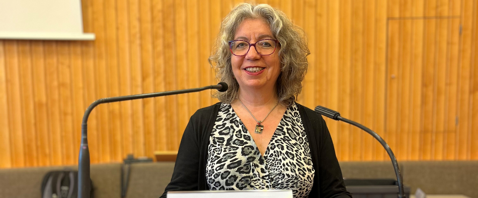 Eine weiblich gelesene Person steht an einem Redepult, an dem vorn "rpi loccum" steht.