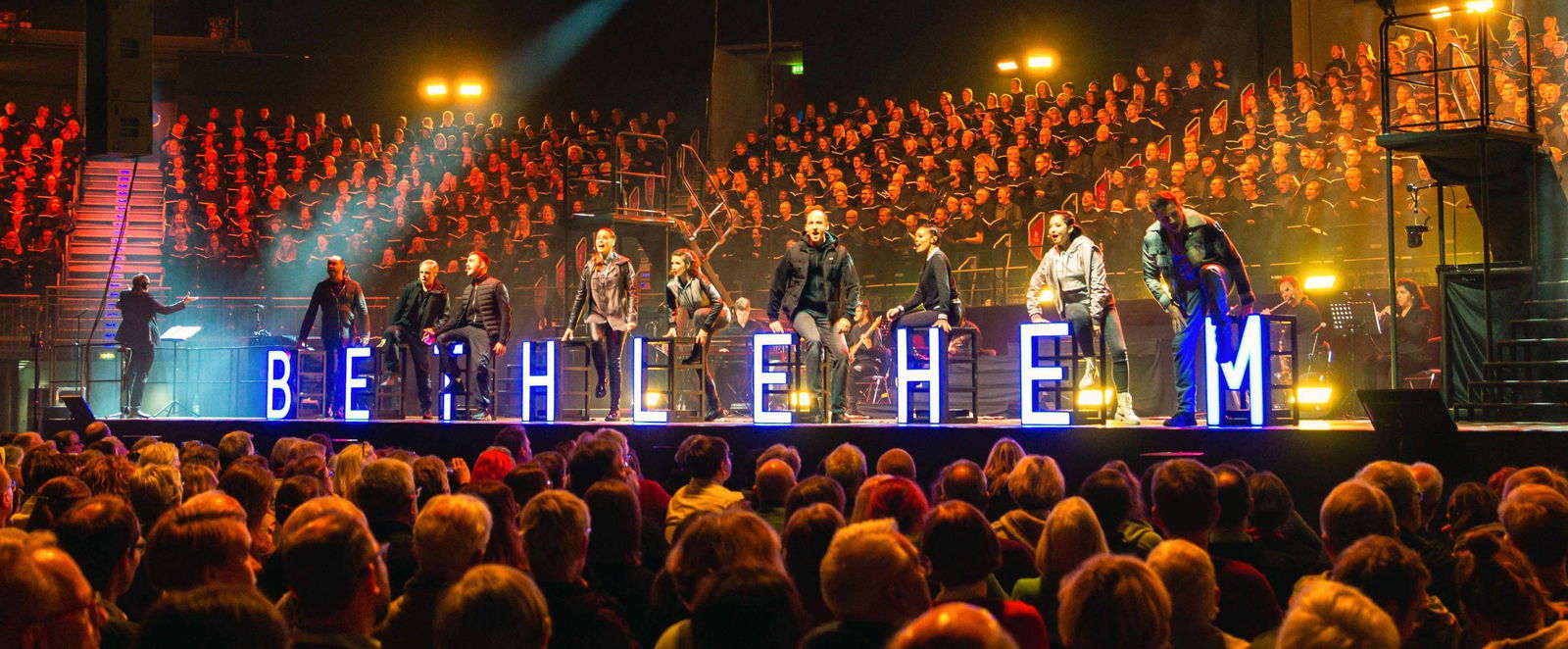 Volles Publikum, Menschen stehen auf einer Bühne, zwischen ihnen das Wort Bethlehem.