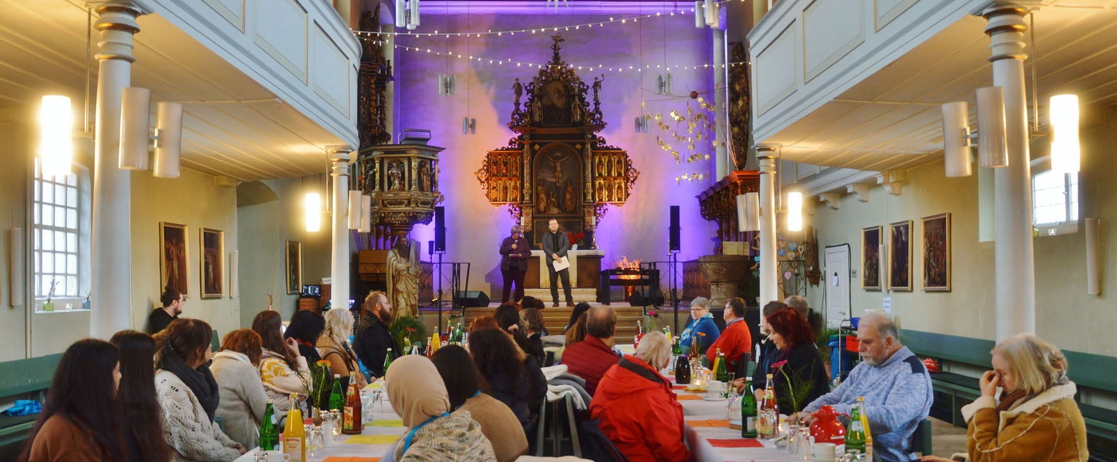 Menschen sitzen an Tischen in einer Kirche.