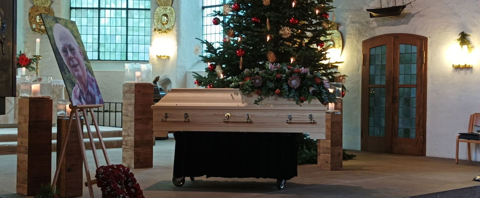 Ein Sarg steht vor einem Weihnachtsbaum in einer Kirche.