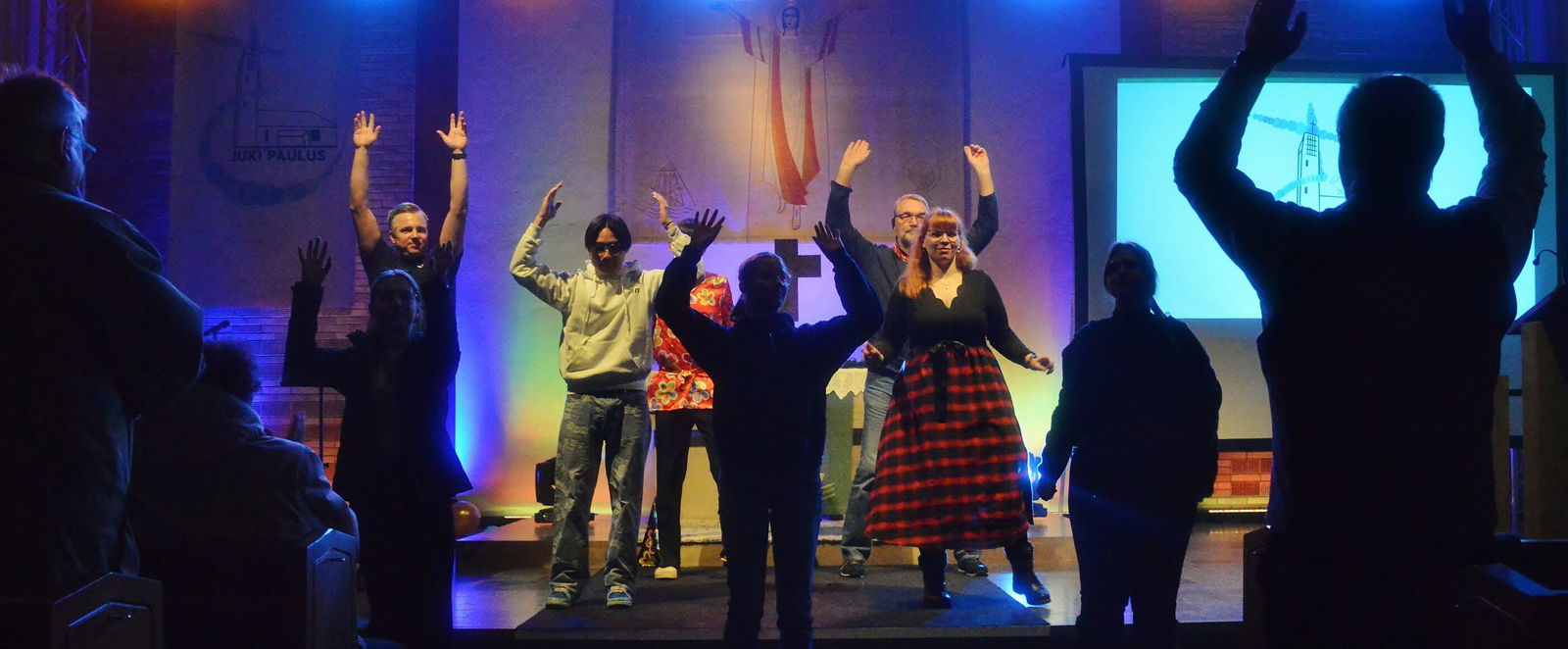 Menschen stehen auf einer Bühne und tanzen. 