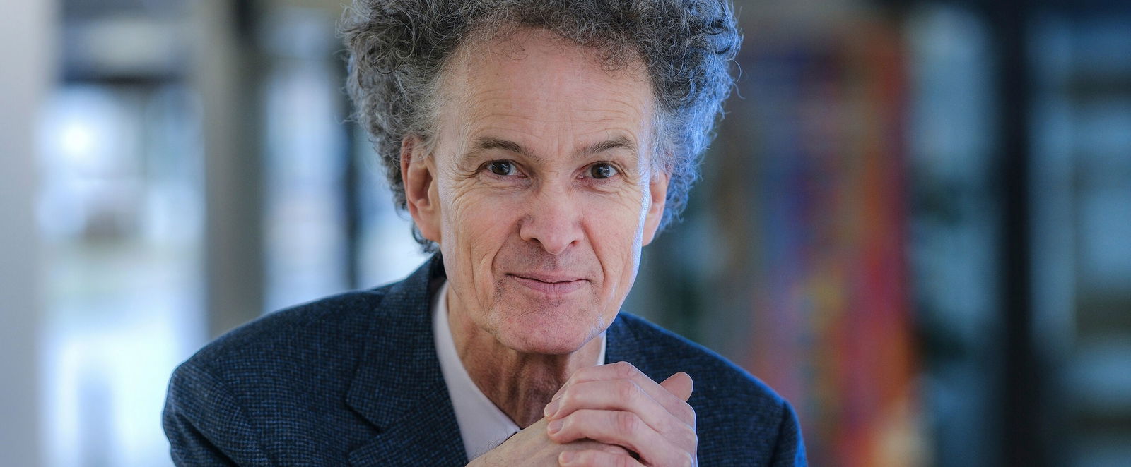 Eine als Mann lesbare Person im Anzug und mit auffälliger Frisur.