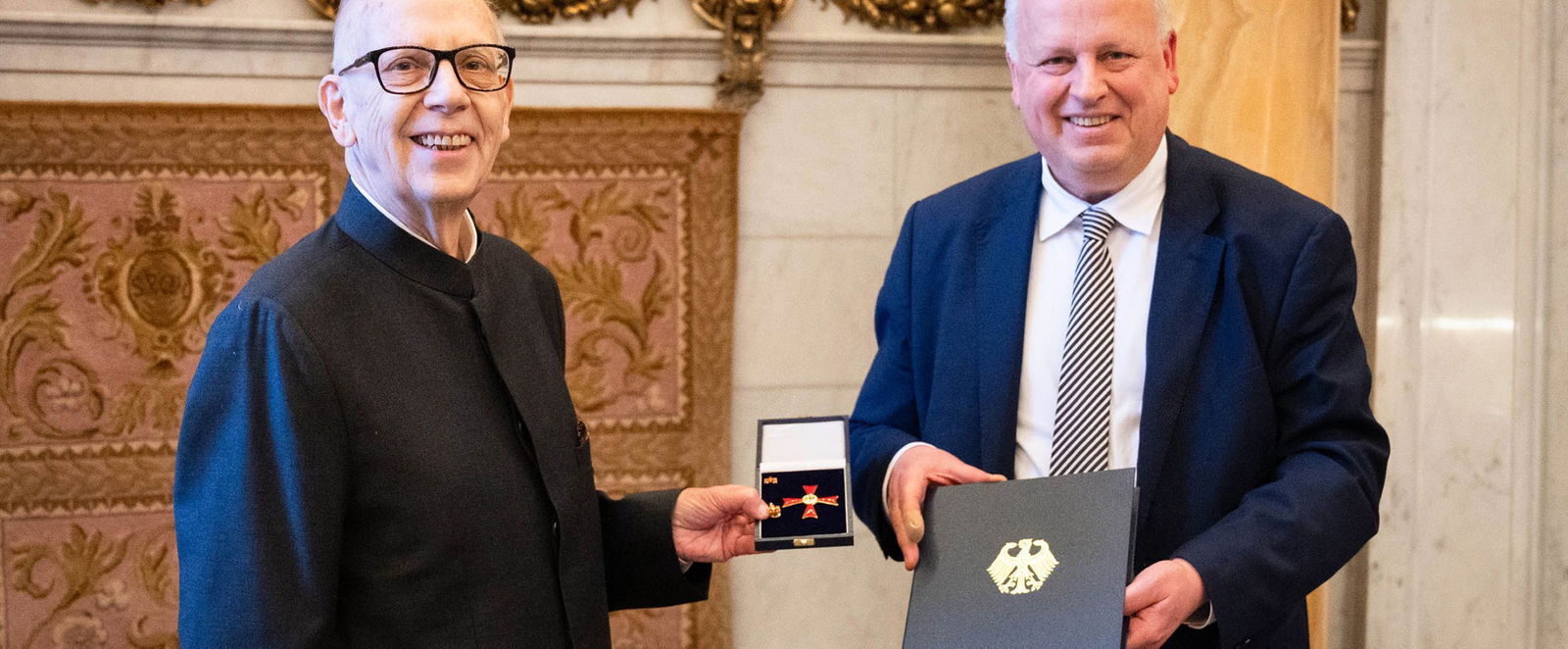 Zwei Männer im Anzug halten eine Auszeichnung.