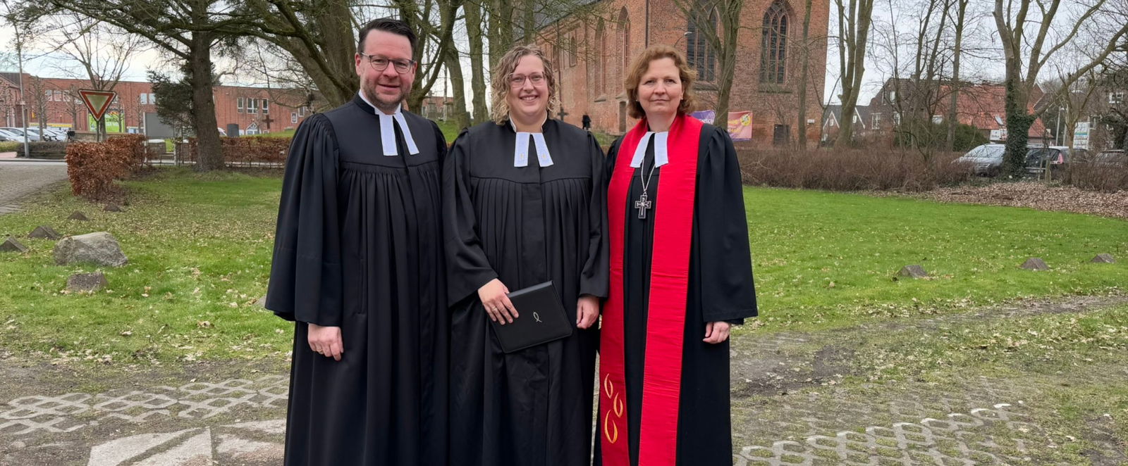 Zwei weibliche und eine männliche Person im Talar.