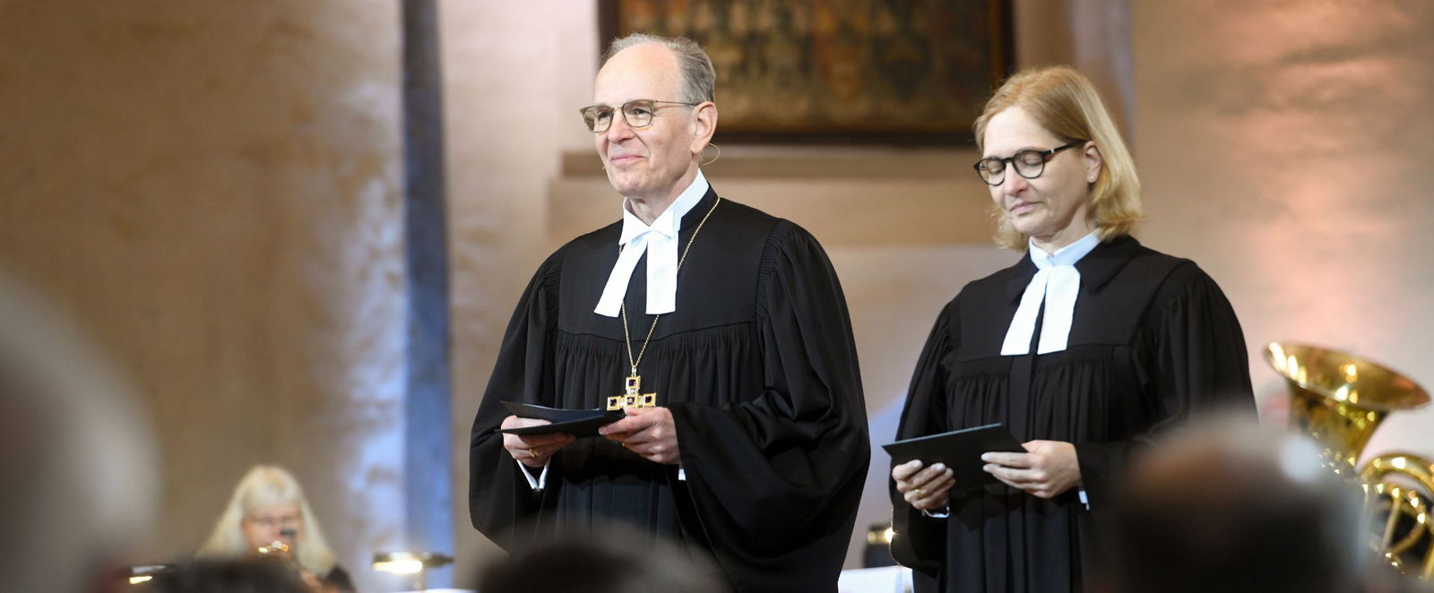 Ein Mann und eine Frau stehen im Talar vor einem Altar.