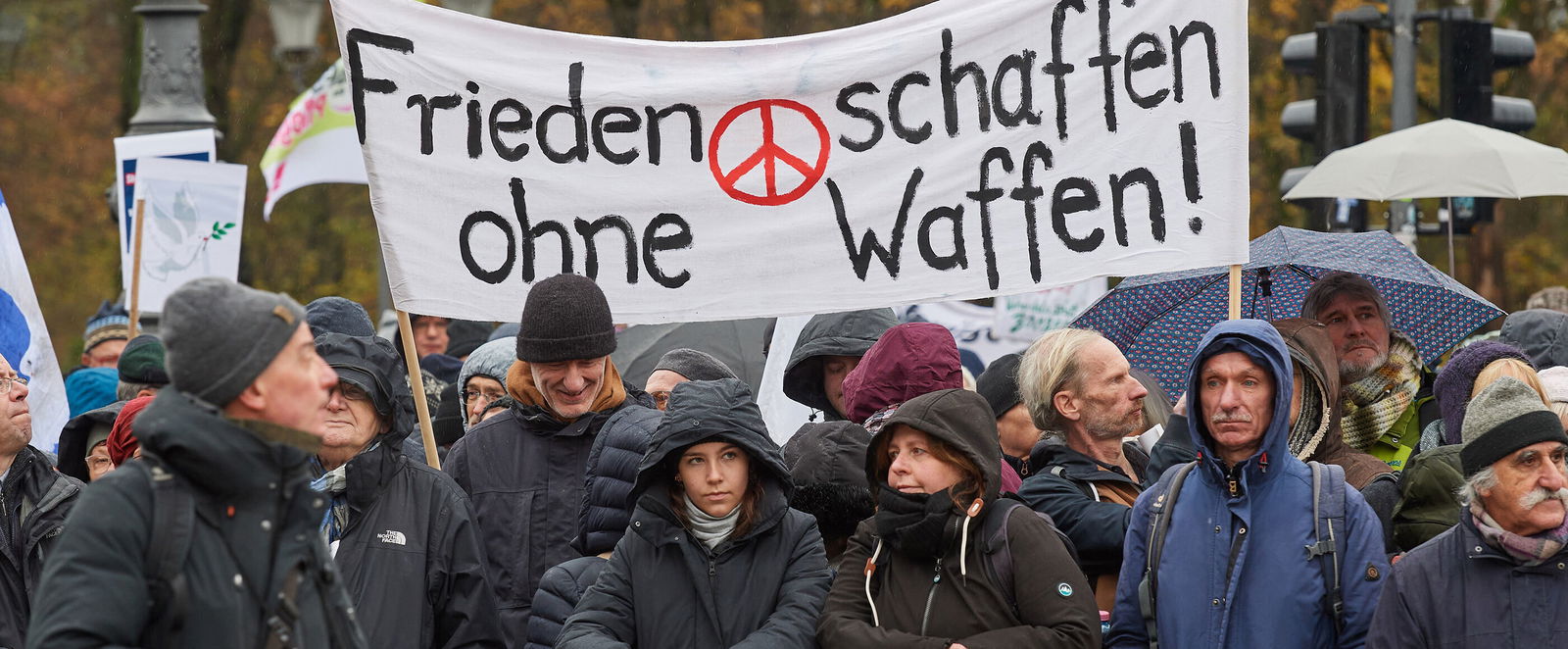 Demonstrierende halten ein Transparent mit der Aufschrift "Frieden schaffen ohne Waffen hoch".