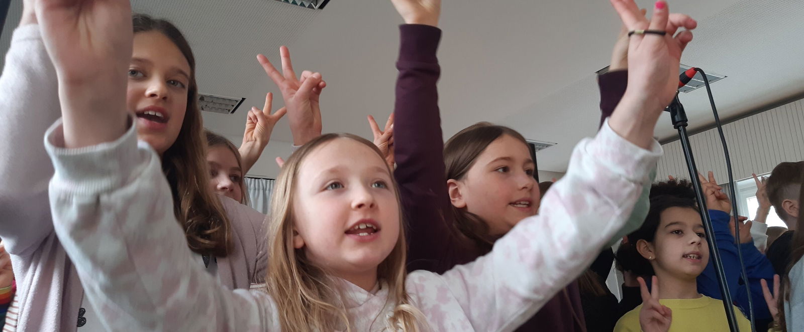 Aus der Froschperspektive: Kinder recken die Arme in die Höhe und schauen fröhlich.