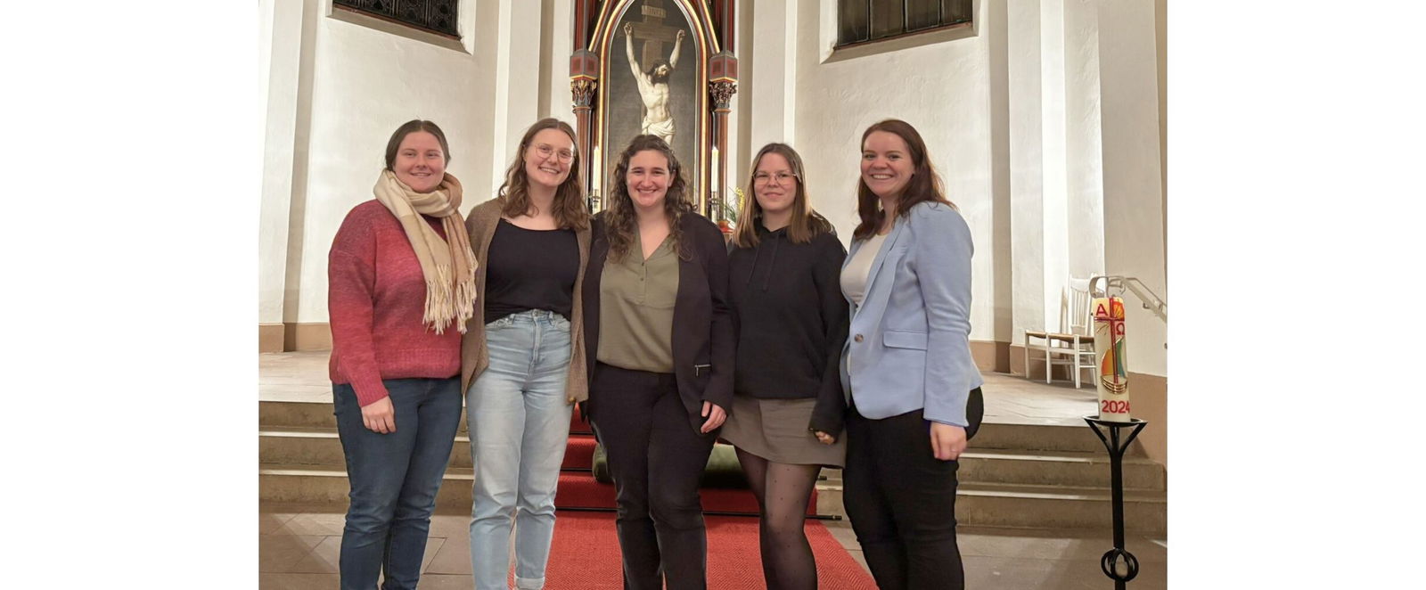 Fünf Frauen stehen lächelnd vor einem Altar.