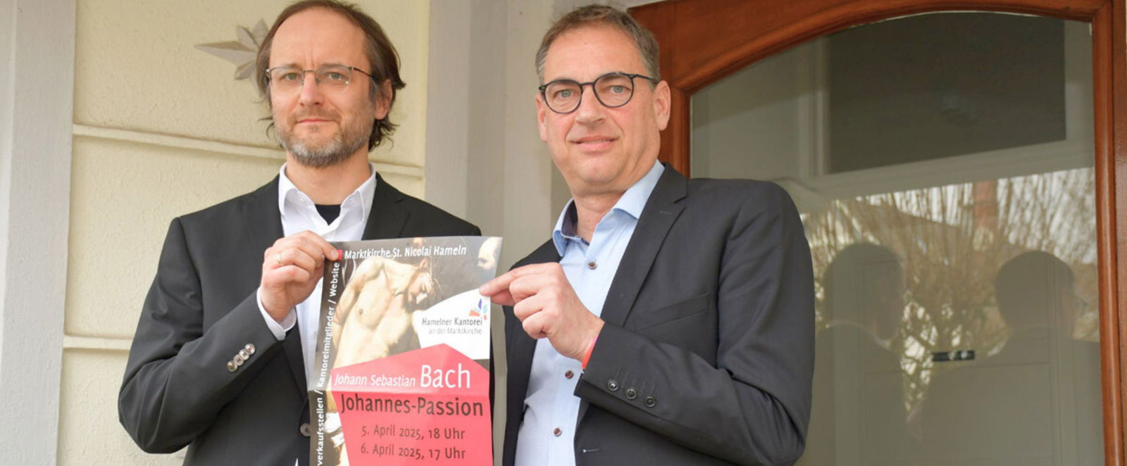zwei Männer halten ein Plakat in der Hand und stehen vor einem Gebäude.