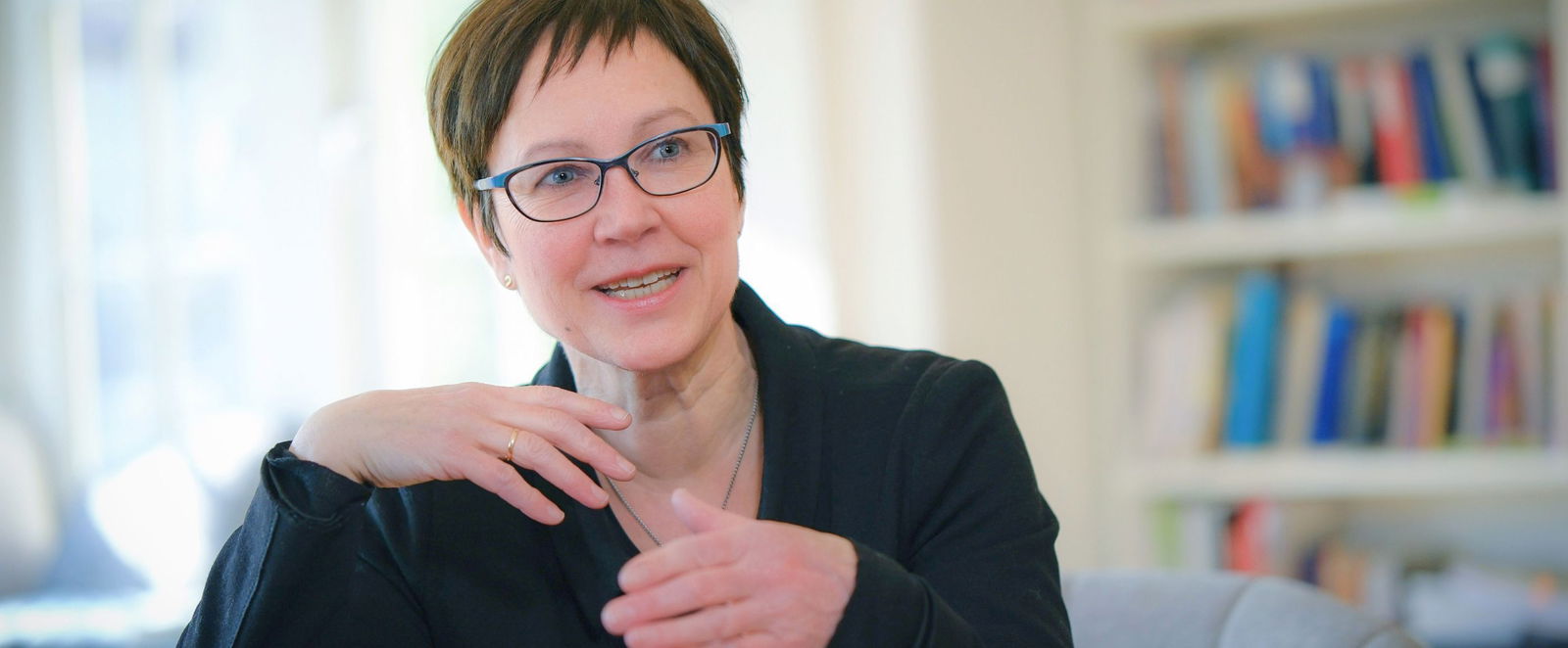 eine Frau in einem Buero vor einem Buecherregal