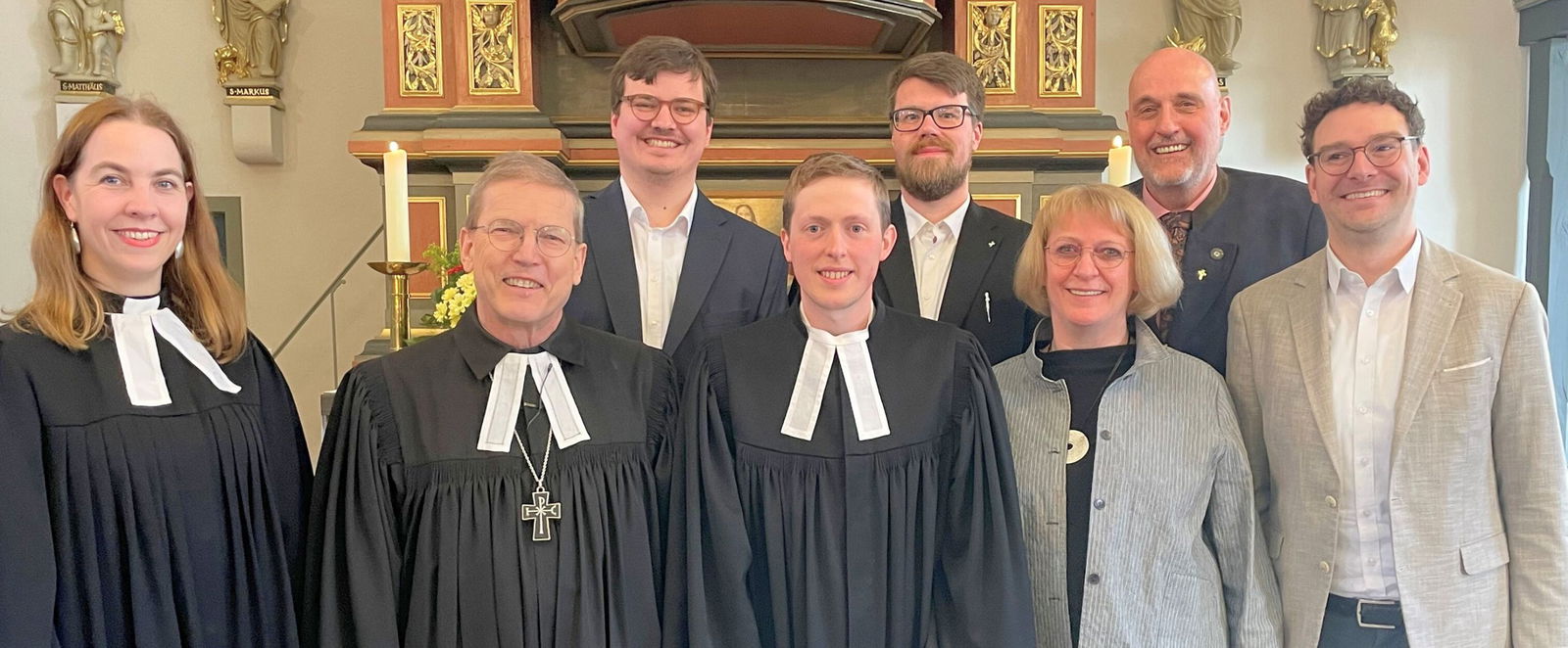 Eine Gruppe Menschen, zum Teil im Talar, stehen in einer Kirche.