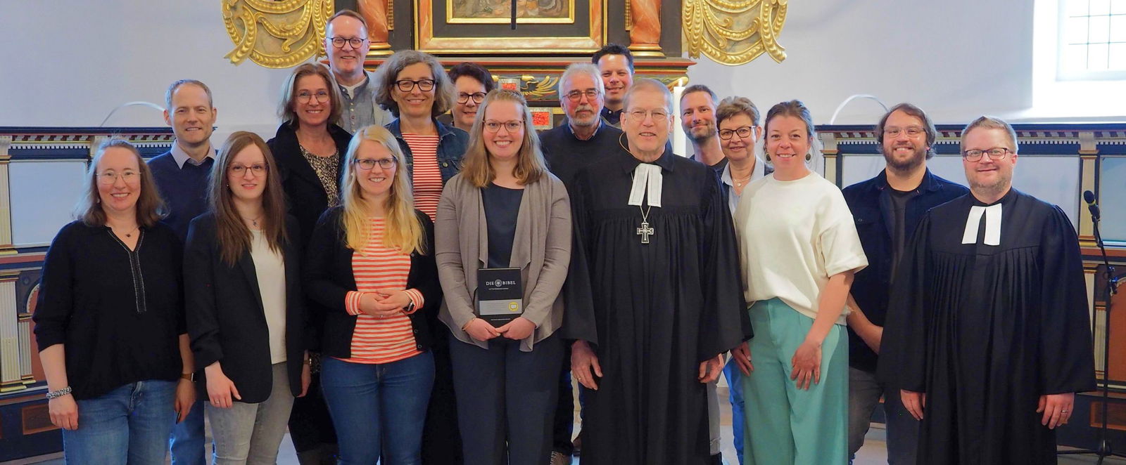 Eine Gruppe Menschen, zum Teil im Talar, steht in einer Kirche.