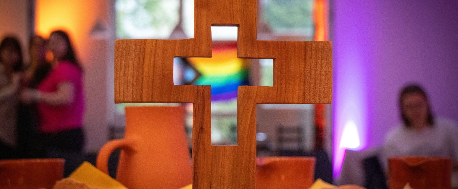 Ein Kreuz durch das man eine Regenbogenfahne sieht.