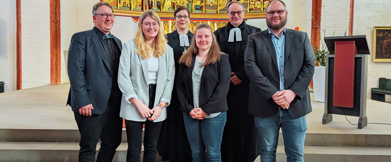 eine Gruppe von Menschen vor einem Kirchenaltar