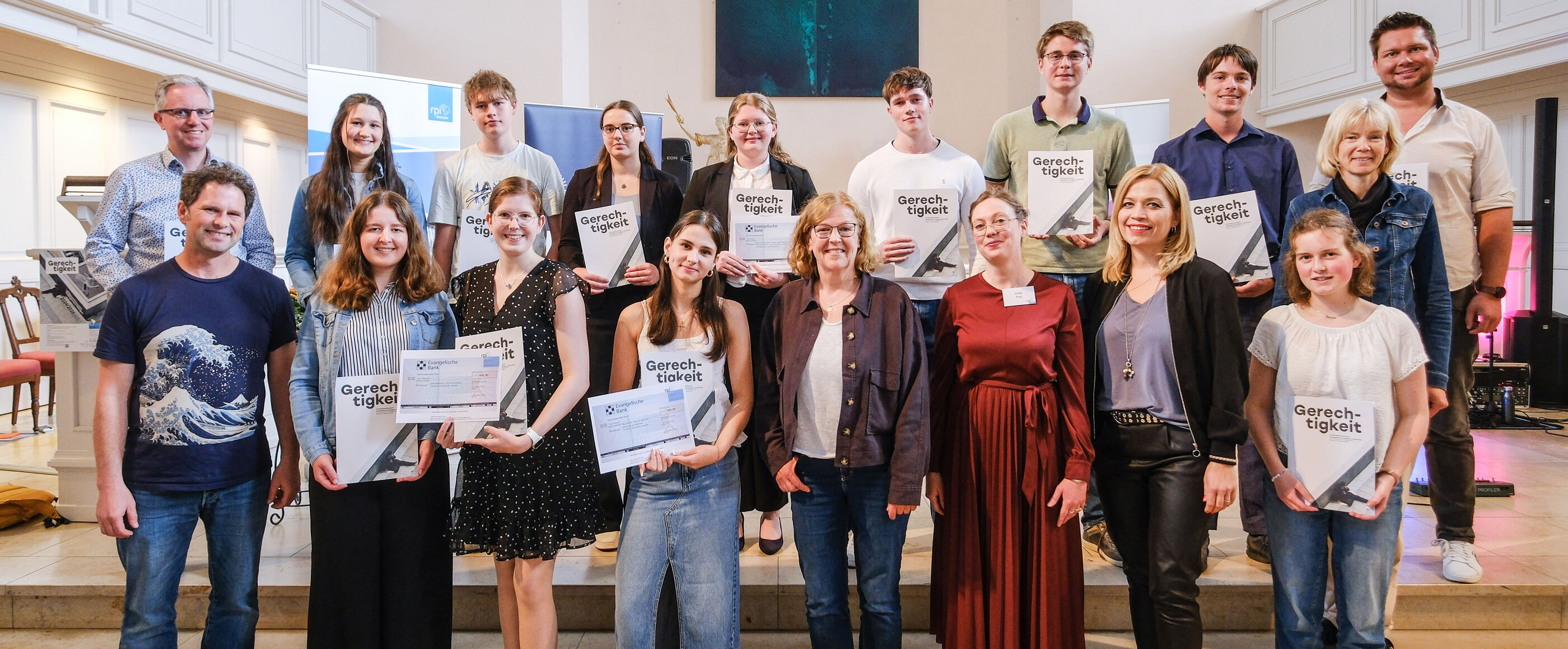 Eine Gruppe junger Menschen steht mit Urkunden und Schecks in einer Kirche.