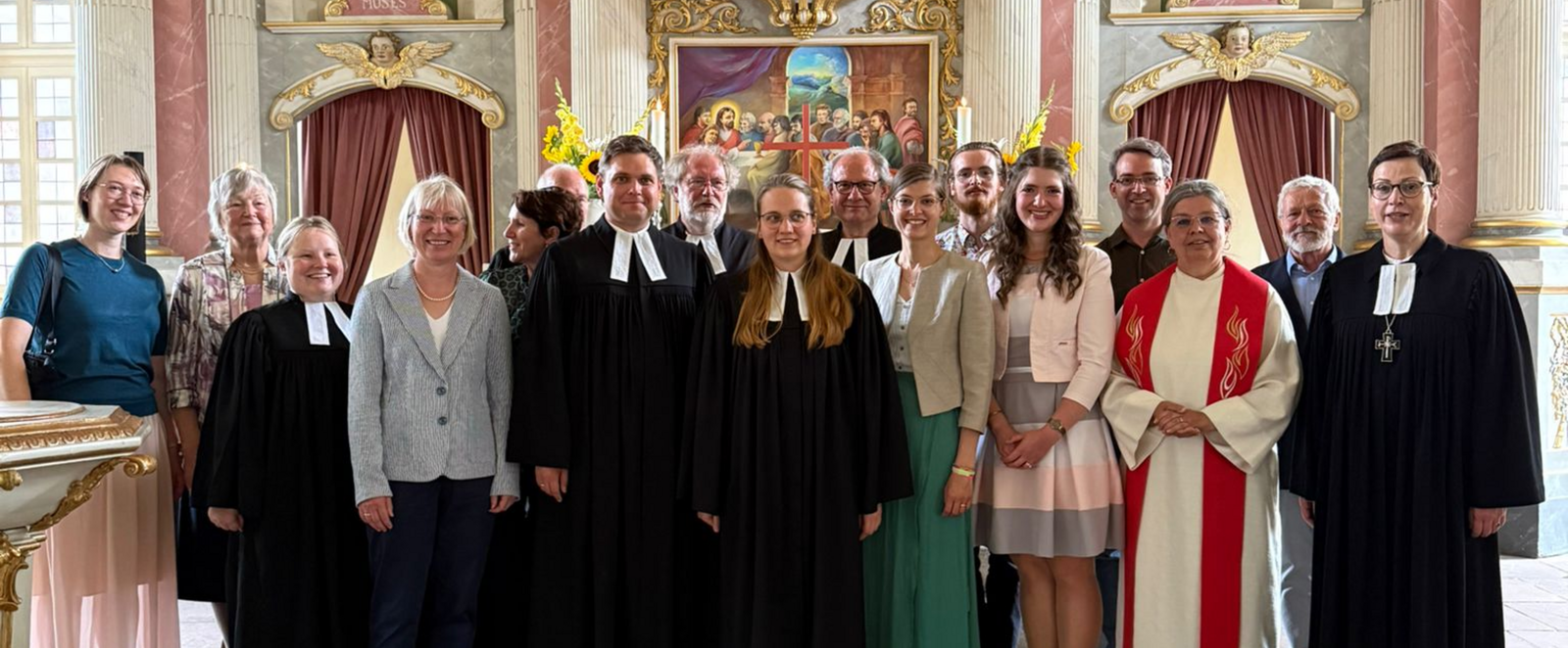 Mehrere Menschen, teils in Talaren, stehen im Altarrraum einer Kirche