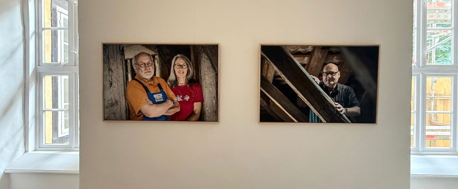 Zwei Fotos hängen an einer Wand.