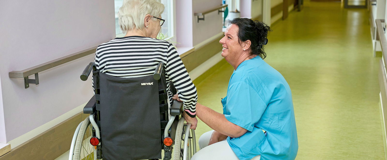 Pflegekraft mit einer Bewohnerin in einem Pflegeheim.