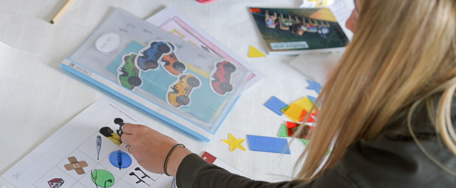 Ein Frau beugt sich über bunte Arbeitsblätter. 