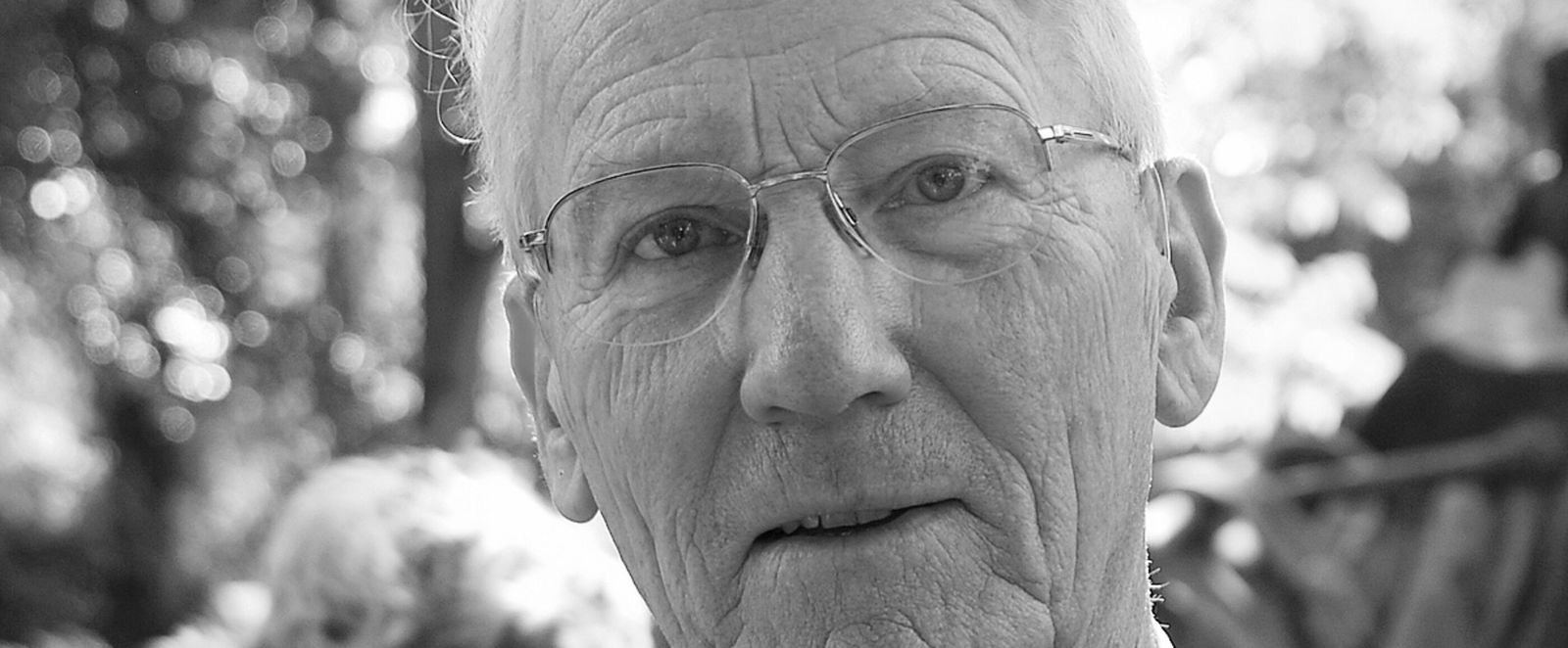 Schwarzweißfoto einer älteren, als Mann lesbaren Person.