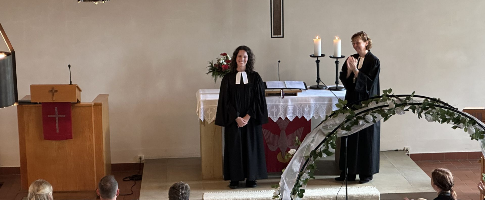 Zwei Personen im Talar stehen in einer Kirche.