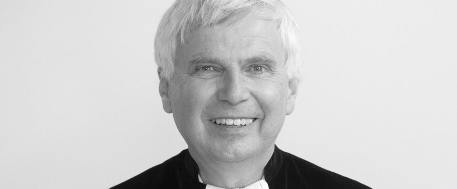 Ein Schwarzweißbild einer als Mann lesbaren Person im Talar.