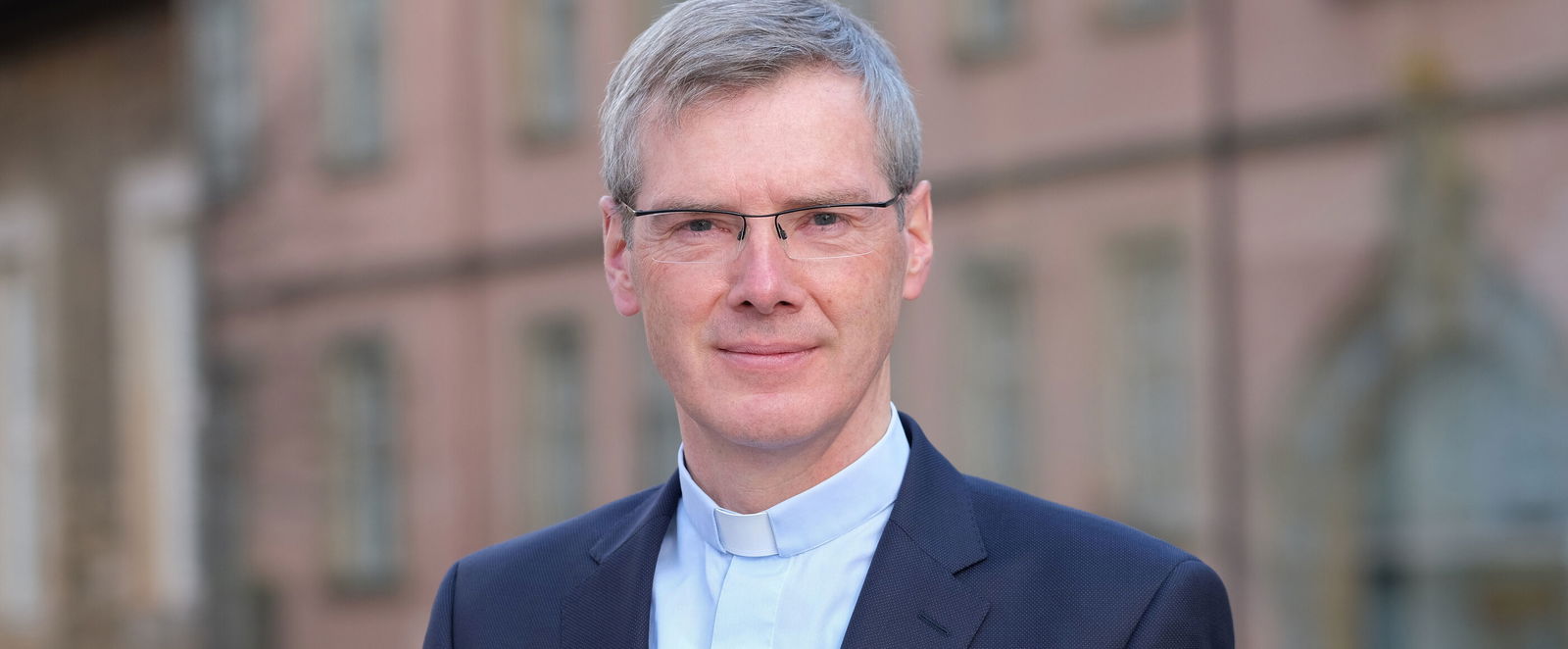 Eine mittelalte als Mann lesbare Person im hellblauen Collarhemd.