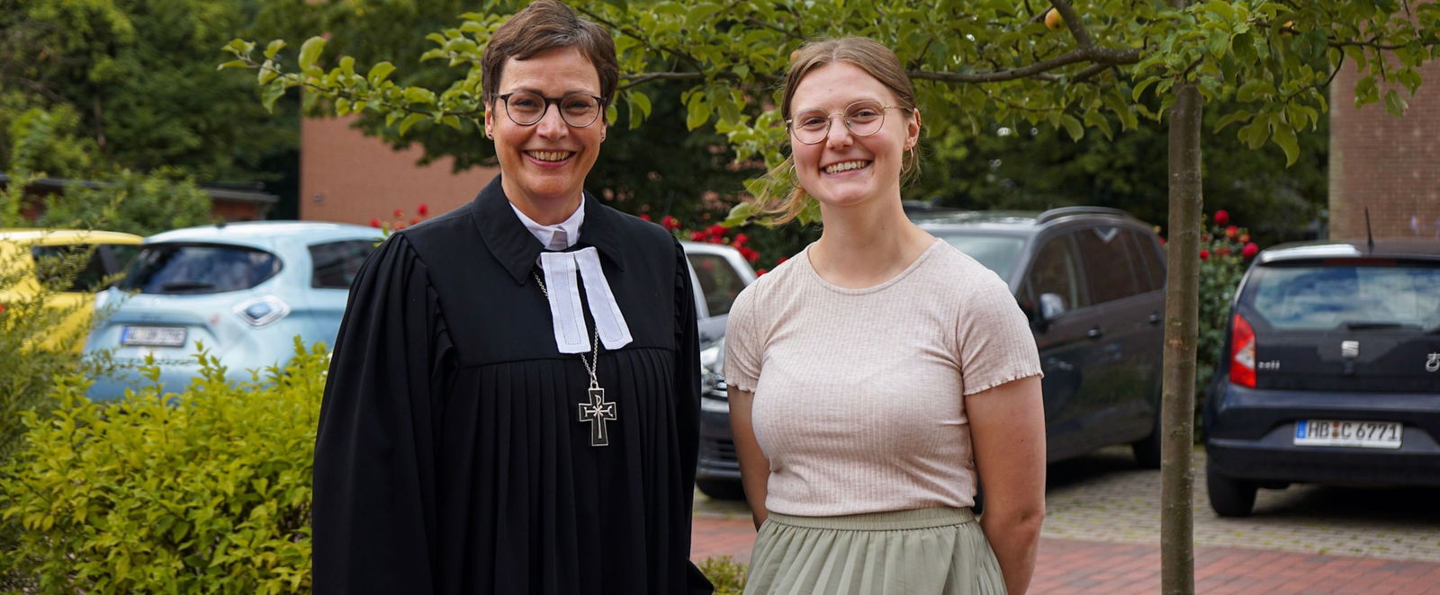 Zwei Frauen lächeln, eine trägt einen Talar.