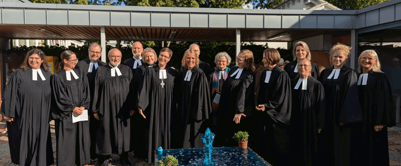 Etwa ein Dutzend Personen in Talaren steht im Freien.