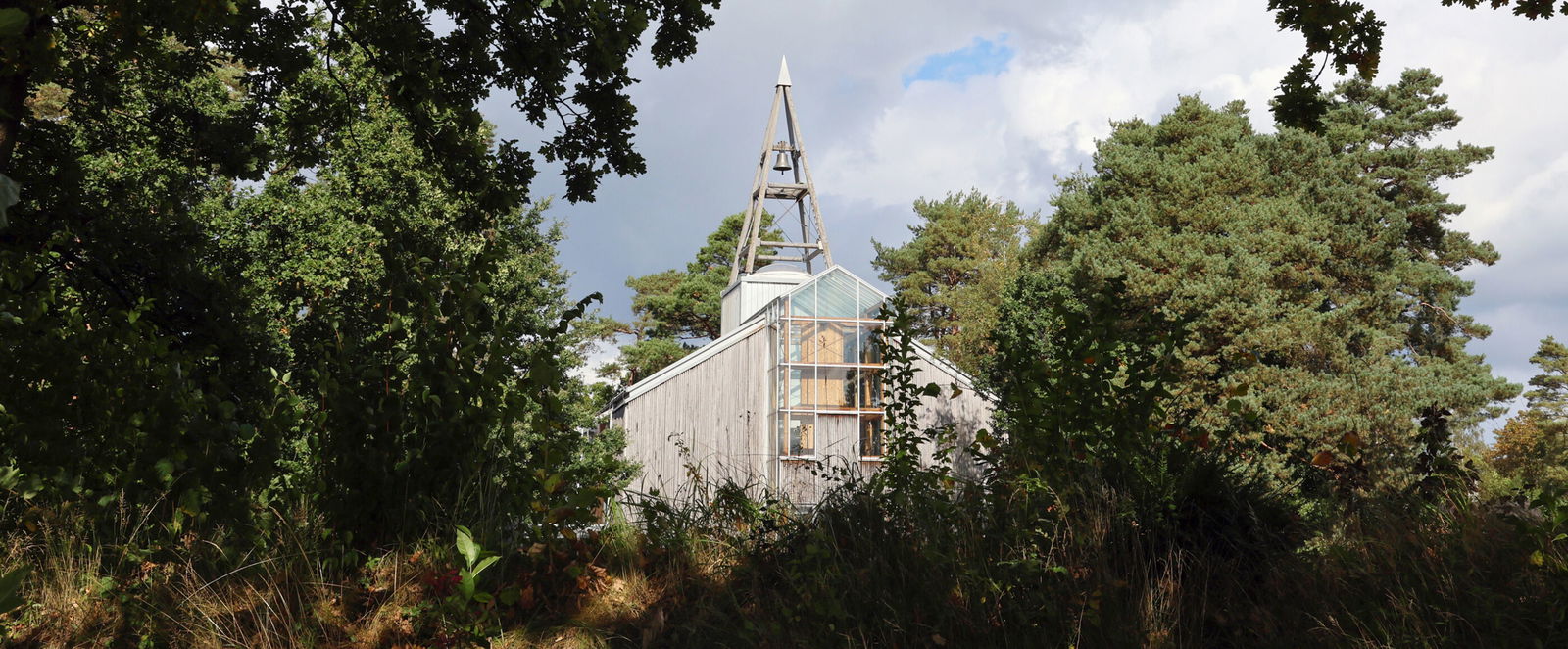 Eine Holzkirche umgeben von Bäumen.