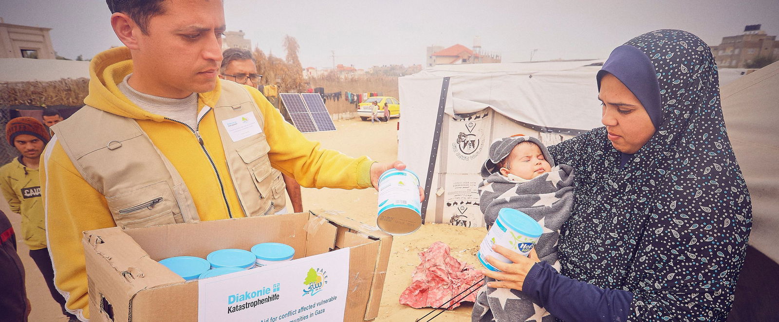Ein Mann reicht einer verschleierten Frau Lebensmittel.