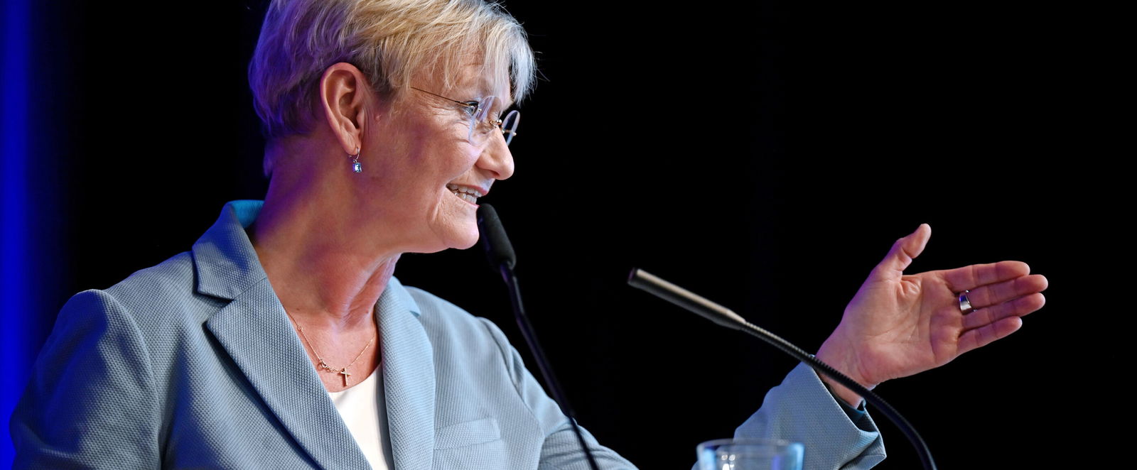 Eine weiblich gelesene Person mit blauem Blazer an einem Mikro.