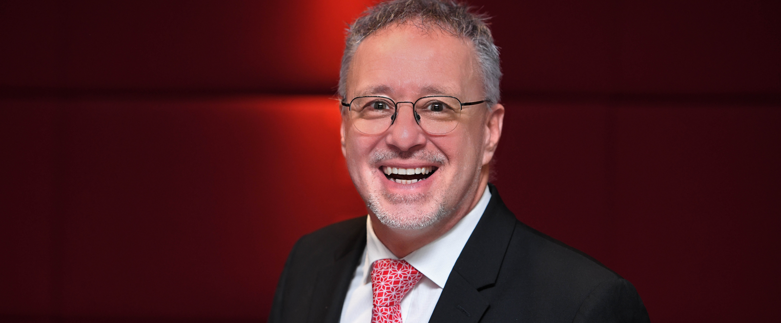 Ein Mann im Anzug mit roter Krawatte.